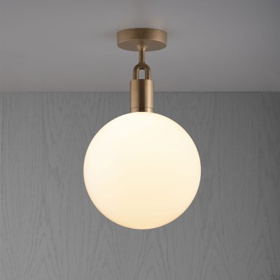 Luminária de teto em latão com formato de L bifurcado e cúpula leitosa.
