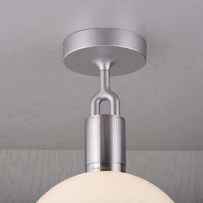 Luminária de teto em aço prateado com formato de L bifurcado e cúpula fosca.